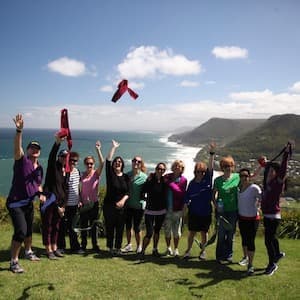 Twelve people make their smiles to the camera in front of a landscape.